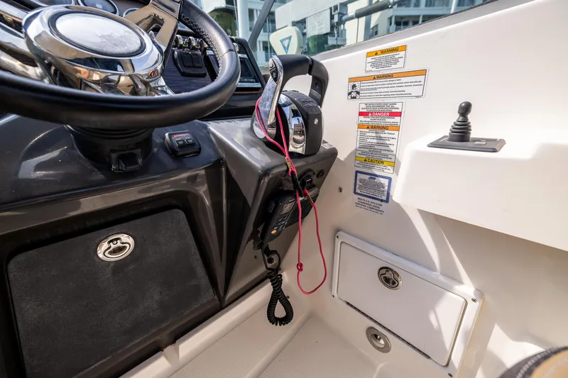 Slide: The Image of 2016 Sea Ray 310 Sundancer helm with steering wheel, throttle controls, and safety warnings. - 43