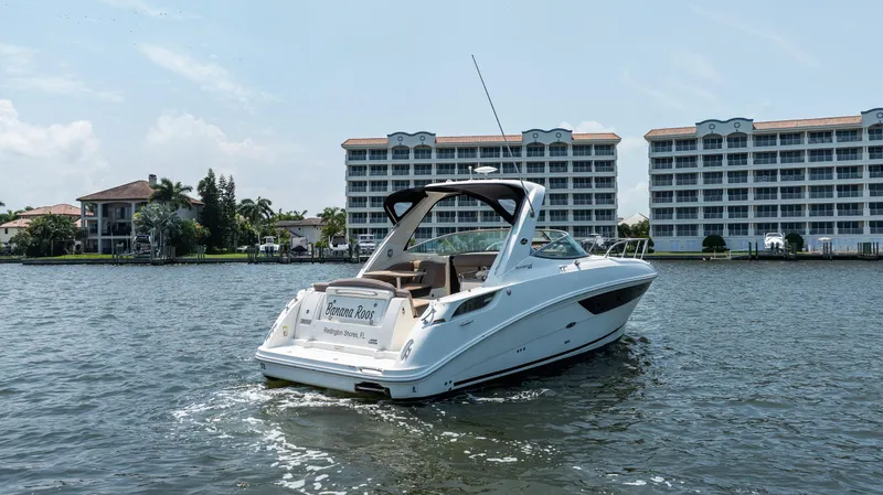 Slide: The Image of 2016 Sea Ray 310 Sundancer boat cruising near waterfront buildings. - 6