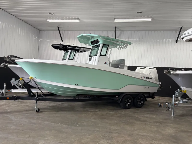 The Image of 2025 Wellcraft 243 Fisherman boat in a showroom, featuring a sleek design and mint green hull. - 1