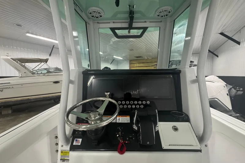 Slide: The Image of 2025 Wellcraft 243 Fisherman boat dashboard with steering wheel and controls in a showroom. - 5
