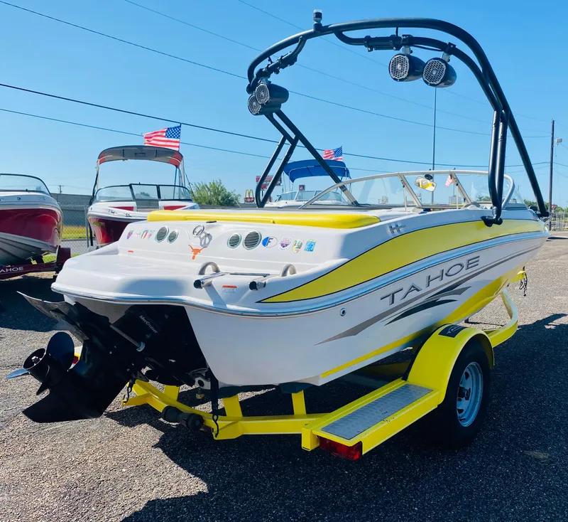 Slide: The Image of 2006 Tahoe Q4 Sport boat with yellow accents on a trailer, displayed outdoors. - 2