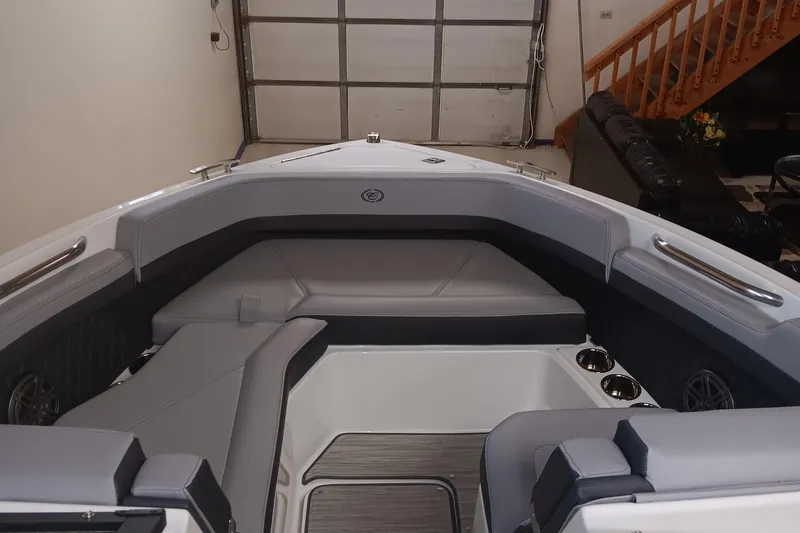 Slide: The Image of 2025 Cobalt R6 boat interior with gray seating and cup holders in a garage setting. - 18