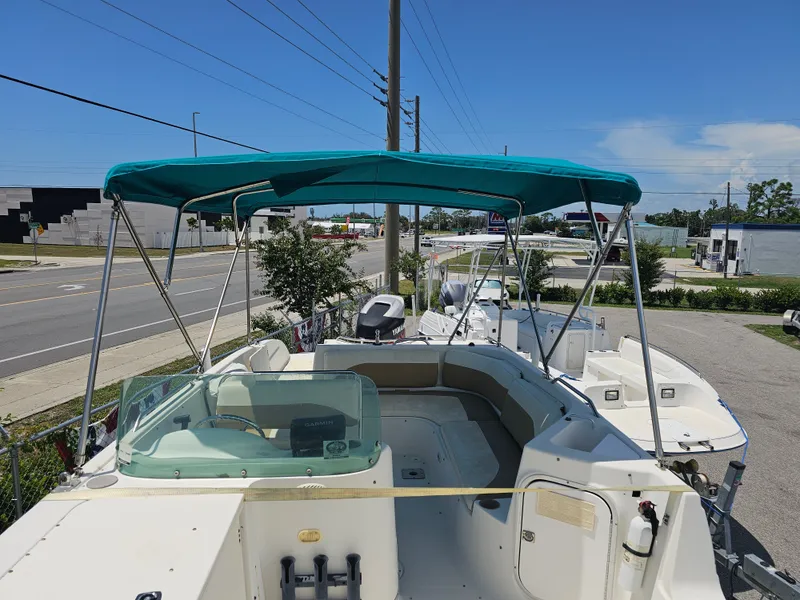 Slide: The Image of 1996 Bayliner 2609 Rendezvous boat with canopy, parked near a road under clear skies. - 15