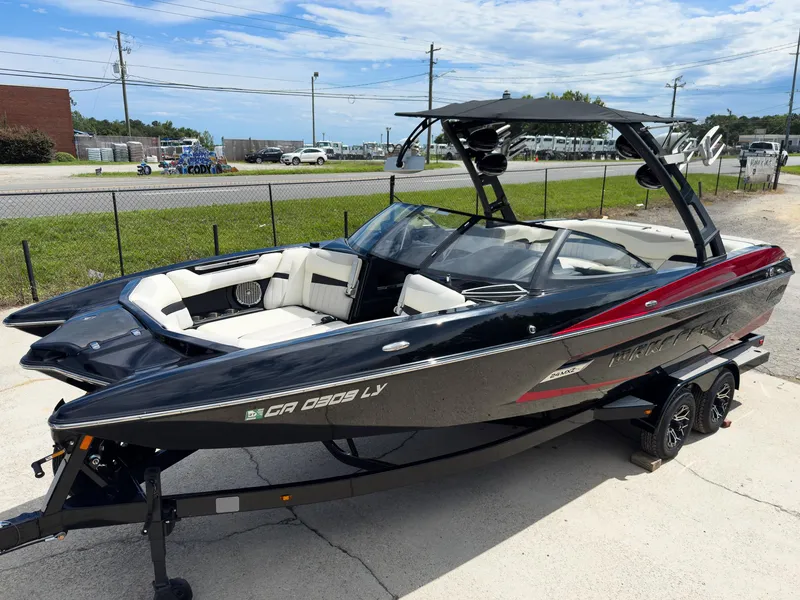 The Image of 2015 Malibu Wakesetter 24 MXZ boat on trailer, black and red design, parked outdoors. - 1