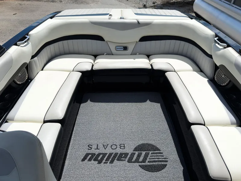 Slide: The Image of 2015 Malibu Wakesetter 24 MXZ interior with white seating and branded carpet. - 22