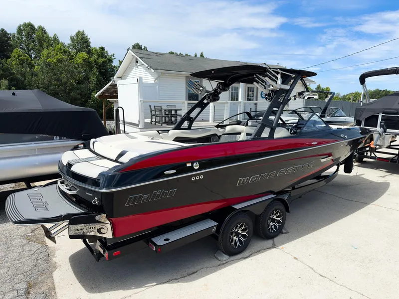 Slide: The Image of 2015 Malibu Wakesetter 24 MXZ boat with red and black design, parked outdoors. - 4