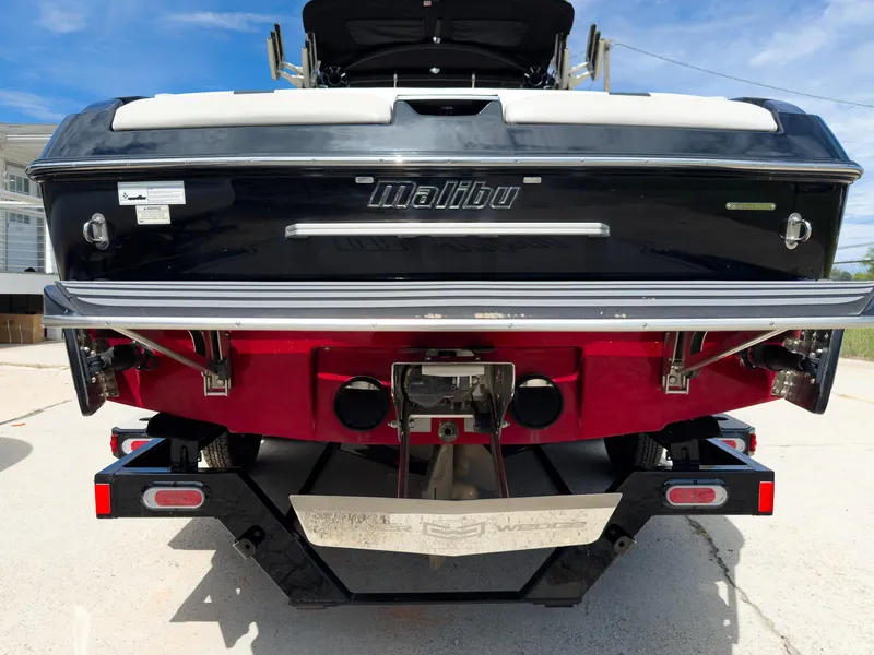 Slide: The Image of 2015 Malibu Wakesetter 24 MXZ boat rear view, showcasing sleek design and trailer. - 6