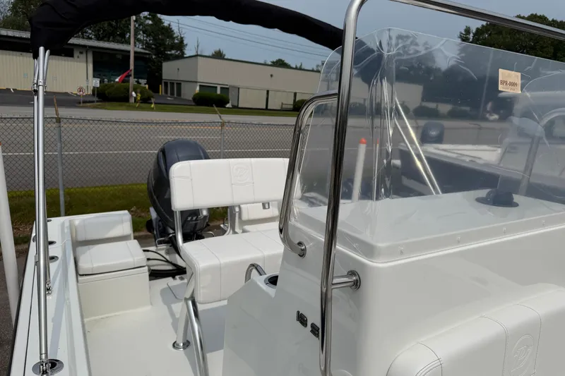 Slide: The Image of 2025 Parker 181 SHOAL boat interior with seating and console, parked near a fence. - 4