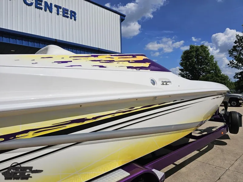 Slide: The Image of 2003 Sunsation 32 Dominator boat with vibrant yellow and purple graphics on trailer. - 10