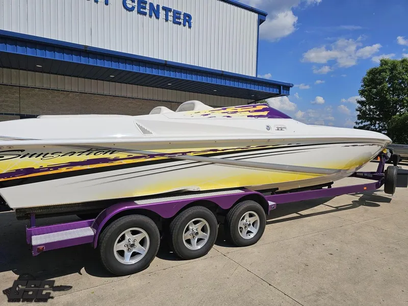 Slide: The Image of 2003 Sunsation 32 Dominator boat on purple trailer, parked outside a building under blue sky. - 11