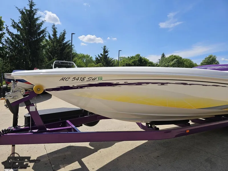 Slide: The Image of 2003 Sunsation 32 Dominator boat on purple trailer, parked outdoors under blue sky. - 16