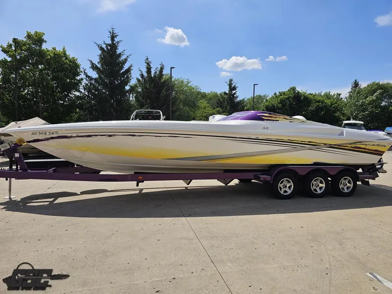 Slide: The Image of 2003 Sunsation 32 Dominator boat on trailer, vibrant design, parked outdoors under blue sky. - 18