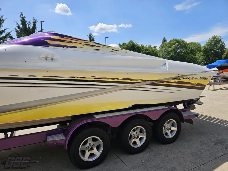 Slide: The Image of 2003 Sunsation 32 Dominator boat on trailer, vibrant graphics, sunny day. - 21