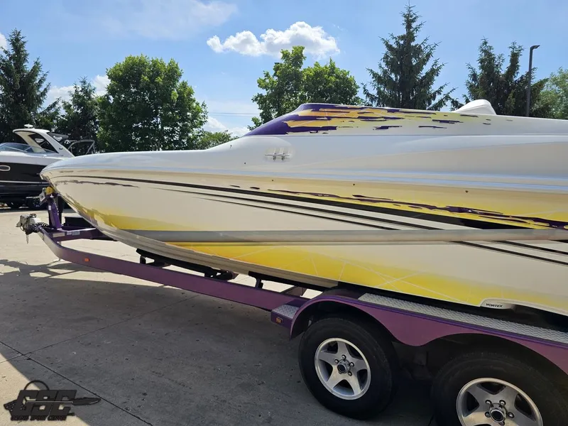 Slide: The Image of 2003 Sunsation 32 Dominator boat on trailer, featuring vibrant yellow and purple design. - 23