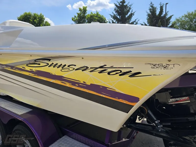 Slide: The Image of 2003 Sunsation 32 Dominator boat with vibrant yellow and purple graphics. - 26