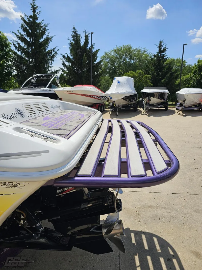 Slide: The Image of 2003 Sunsation 32 Dominator boat with purple swim platform in a marina setting. - 27
