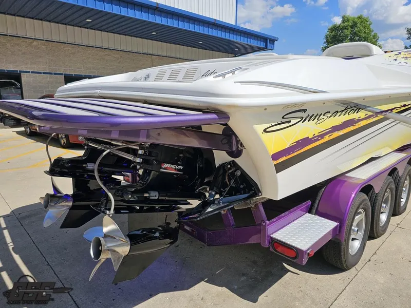 Slide: The Image of 2003 Sunsation 32 Dominator boat with vibrant graphics and powerful Mercury engines. - 33