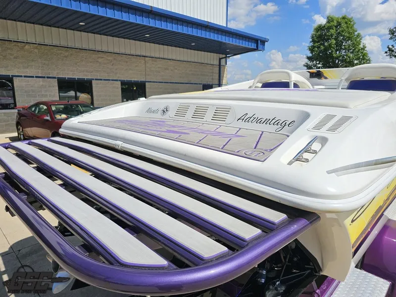Slide: The Image of 2003 Sunsation 32 Dominator boat with purple accents, parked outdoors under a blue sky. - 35