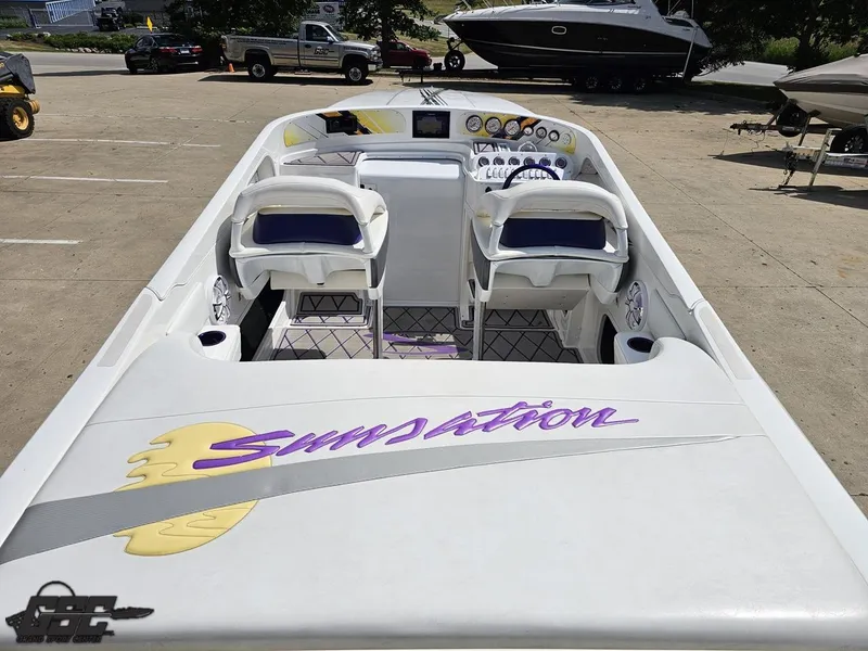 Slide: The Image of 2003 Sunsation 32 Dominator boat interior with white and purple seating, parked outdoors. - 41