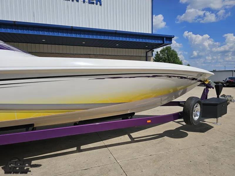 Slide: The Image of 2003 Sunsation 32 Dominator boat on a purple trailer, parked outside a building under a blue sky. - 6