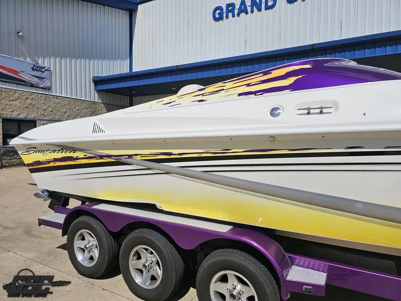 Slide: The Image of 2003 Sunsation 32 Dominator boat with vibrant purple and yellow design on a trailer. - 8