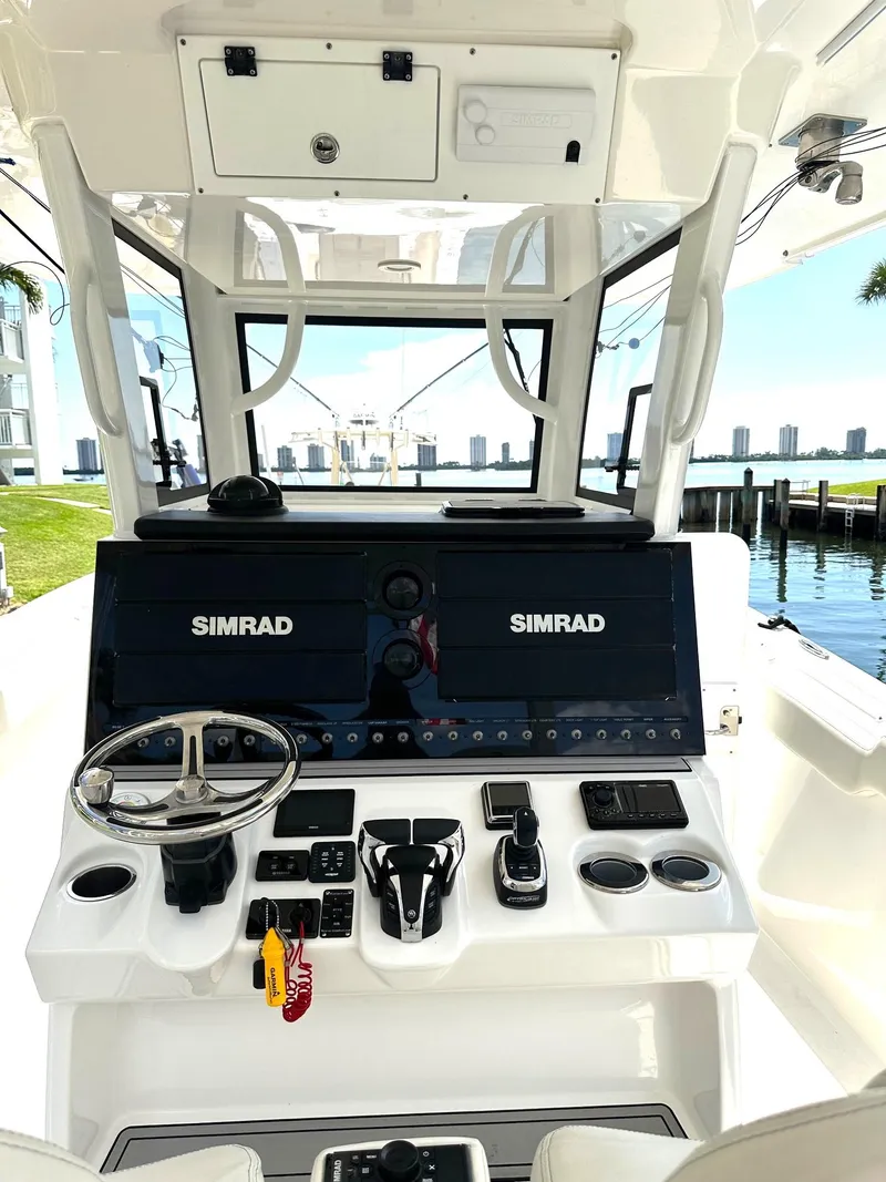 Slide: The Image of 2022 Sea Pro 320 DLX Center Console with dual Simrad displays, docked by waterfront. - 21