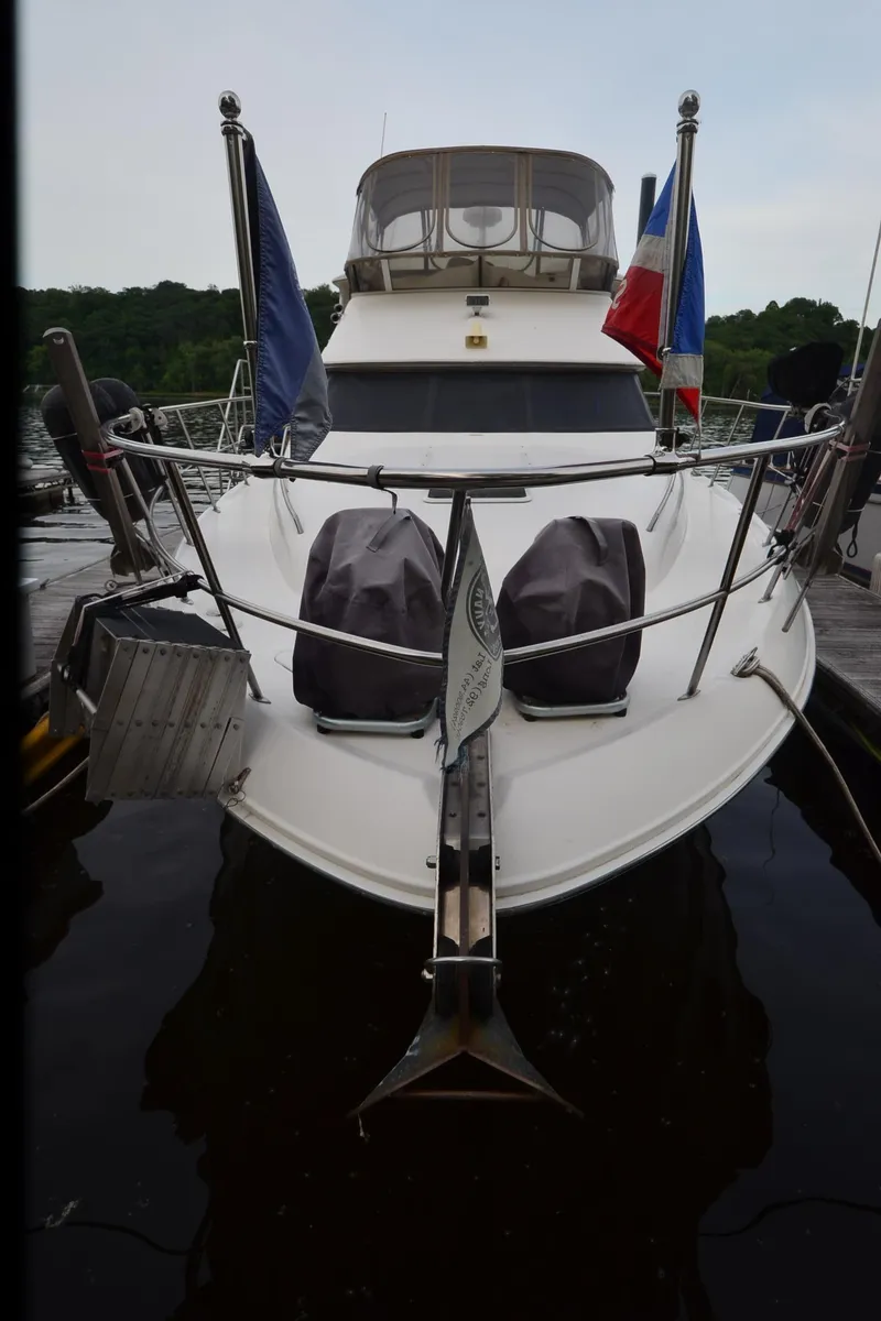 Slide: The Image of 2000 Sea Ray 420 Aft Cabin yacht docked, front view with flags and covered equipment. - 45