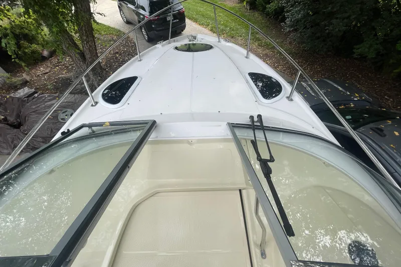 Slide: The Image of 2019 Regal 28 Express boat deck with open windshield, surrounded by trees and parked cars. - 20
