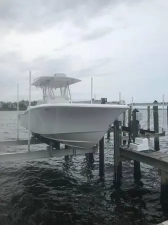 Slide: The Image of 2020 Invincible 33 Open Fisherman boat docked on a lift by the water. - 2