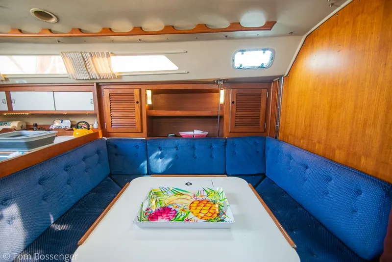 Slide: The Image of Interior of 1988 Catalina 36 sailboat with blue cushioned seating and wooden cabinetry. - 14