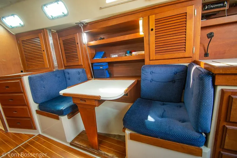 Slide: The Image of 1988 Catalina 36 interior with blue cushioned seating and wooden cabinetry. - 16