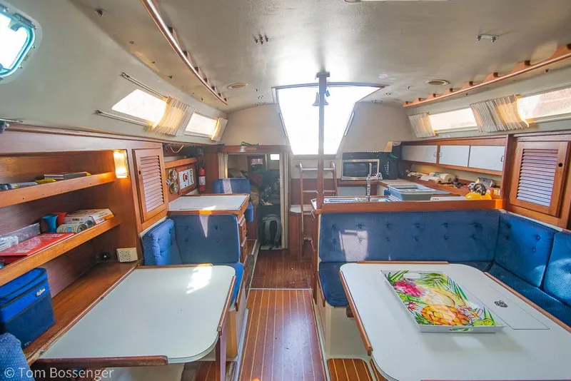 Slide: The Image of Interior of 1988 Catalina 36 sailboat with blue seating, wooden accents, and dining area. - 24