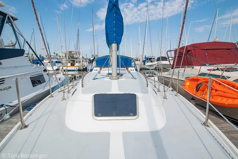 Slide: The Image of 1988 Catalina 36 sailboat docked in a marina, surrounded by other boats under a blue sky. - 47