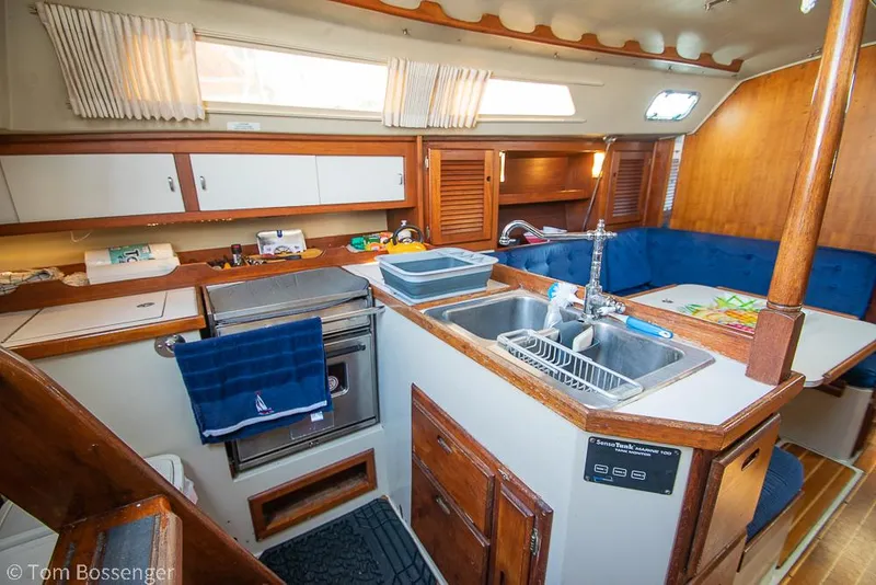 Slide: The Image of Interior of 1988 Catalina 36 sailboat featuring kitchen and dining area with wood accents. - 6