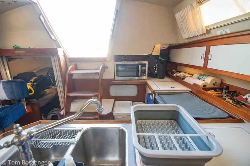 Slide: The Image of Interior of 1988 Catalina 36 sailboat kitchen with sink, microwave, and storage. - 7