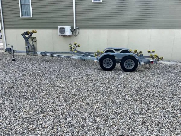 Slide: The Image of Trailer for 2023 Sea Hunt Ultra 234 on gravel driveway, near a building. - 6