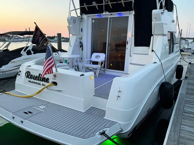 Slide: The Image of 2001 Silverton 351 Sedan Cruiser docked at sunset, featuring American flag and deck chairs. - 13