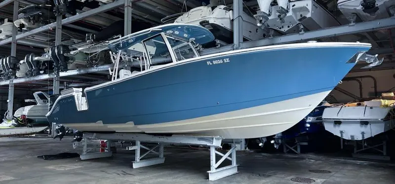 The Image of 2018 Cobia 344 Center Console boat in storage, blue hull, elevated on stands. - 1