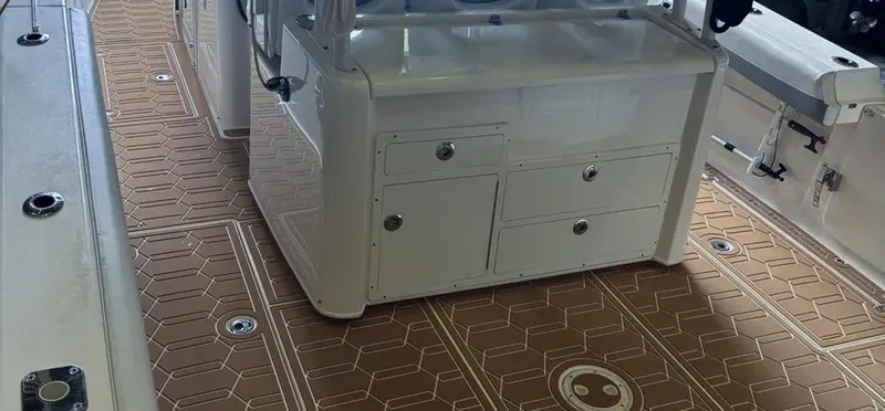 Slide: The Image of 2018 Cobia 344 Center Console boat interior with brown patterned flooring and white storage console. - 7