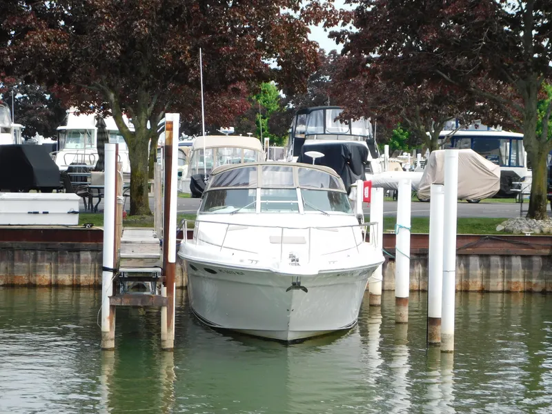 Slide: The Image of 1997 Sea Ray 330 Sundancer docked at marina, surrounded by trees and other boats. - 14