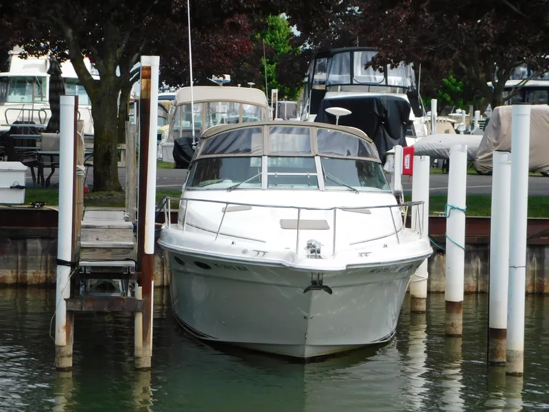 Slide: The Image of 1997 Sea Ray 330 Sundancer docked at marina, surrounded by trees and other boats. - 15