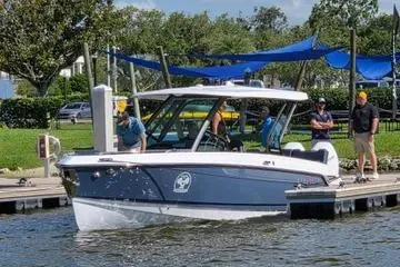Slide: The Image of 2025 Monterey Elite 30 OB boat docked with people nearby, under blue canopies. - 9