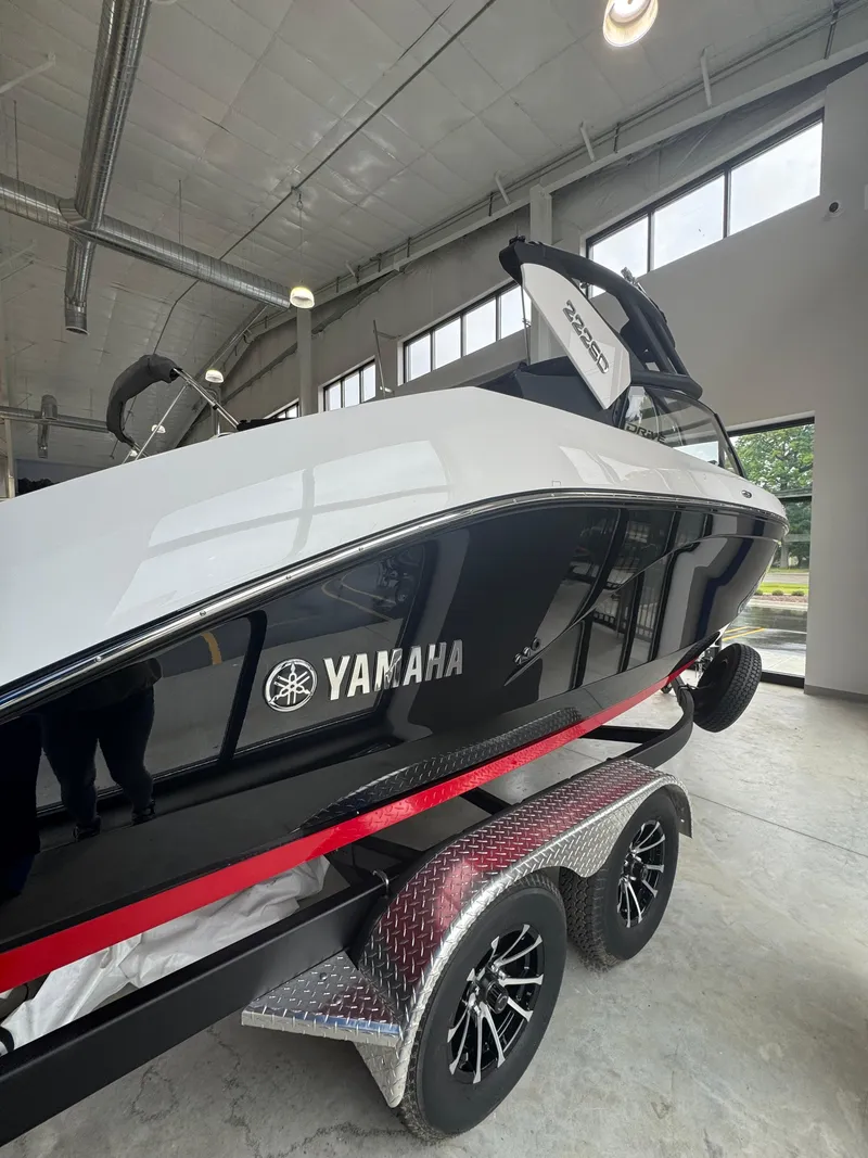 Slide: The Image of 2025 Yamaha Boats 222SD on trailer in showroom, sleek black and white design. - 1