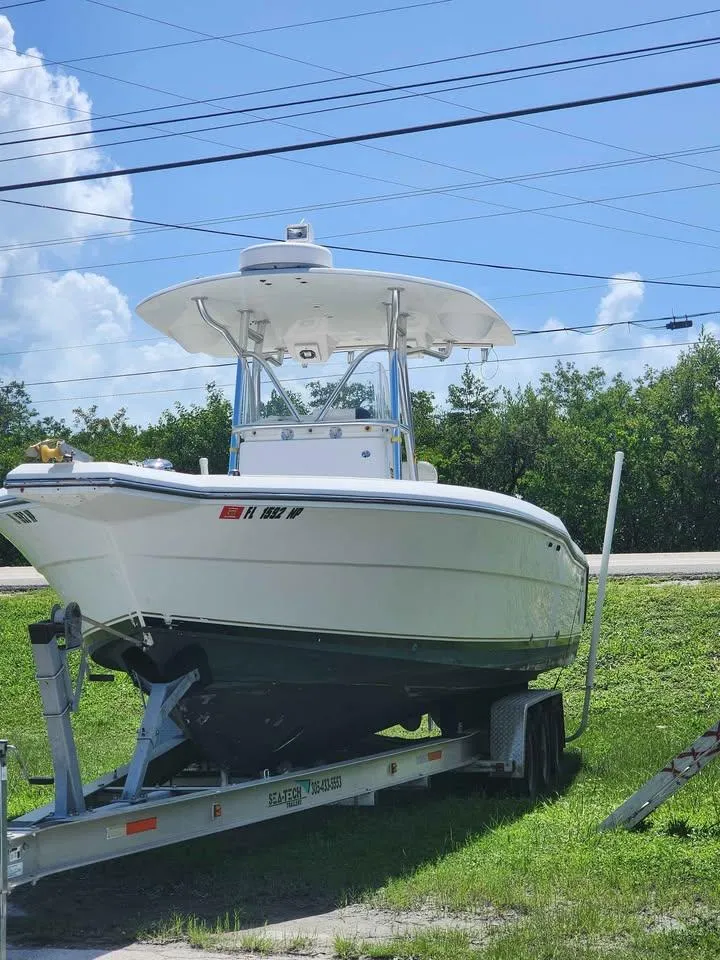Slide: The Image of 2006 Stamas 290 Tarpon boat on trailer, parked on grass under blue sky. - 10