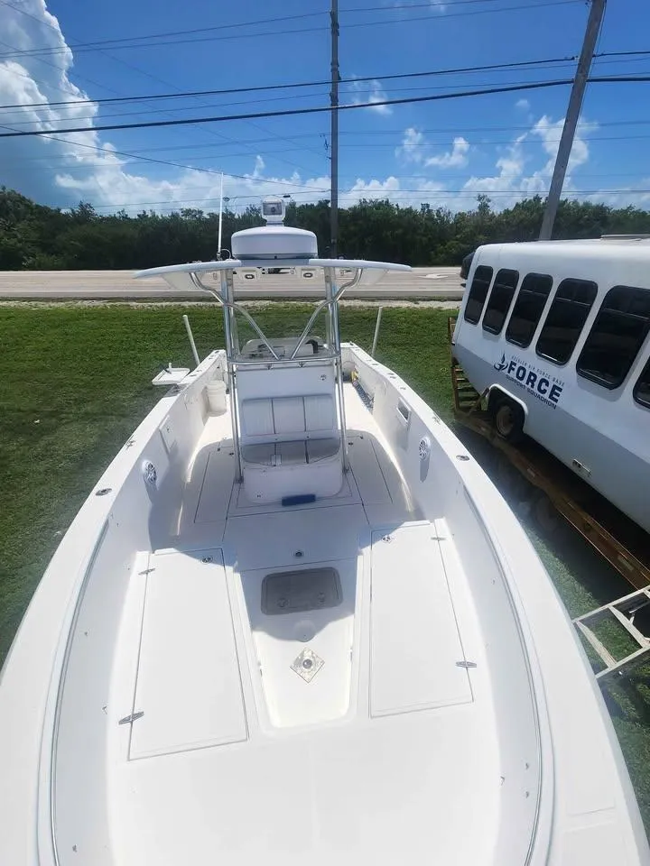 Slide: The Image of 2006 Stamas 290 Tarpon boat with T-top, parked on grass near a white bus. - 9