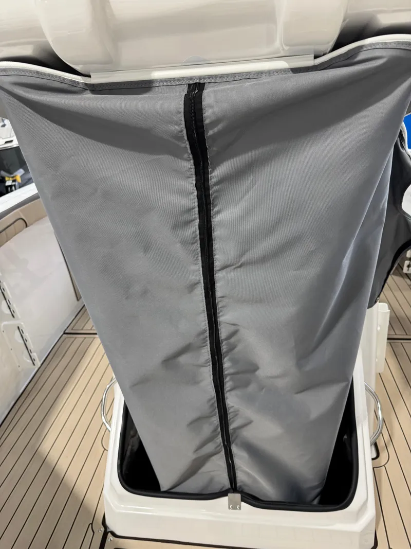 Slide: The Image of 2025 Yamaha Boats 255 FSH Sport E storage compartment with gray cover and zipper. - 18