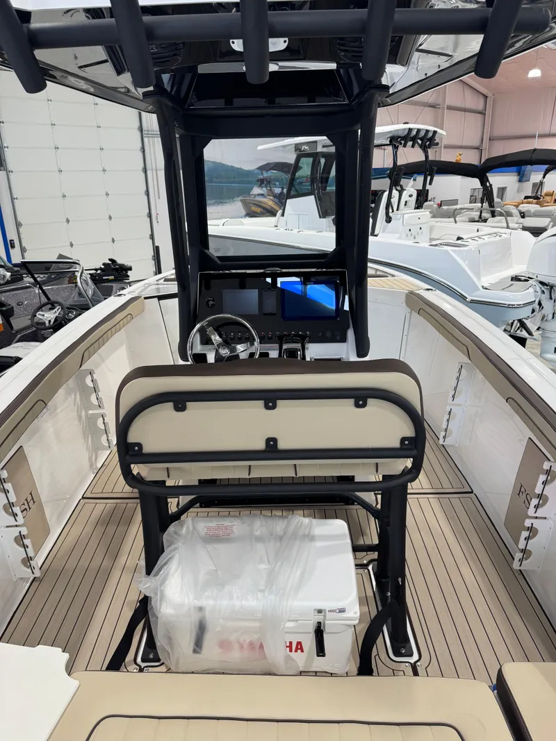 Slide: The Image of 2025 Yamaha Boats 255 FSH Sport E interior with helm and seating in a showroom. - 5