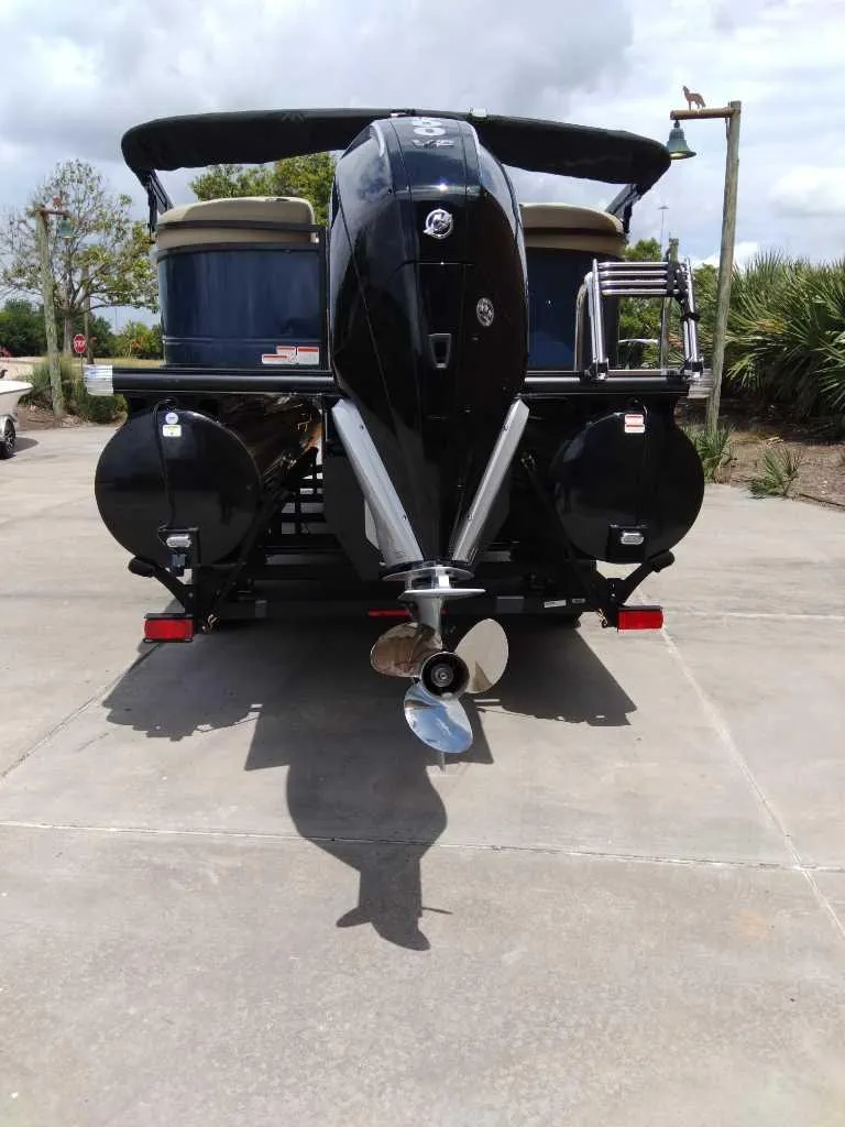 Slide: The Image of 2025 Regency 250 LE3 pontoon boat with powerful outboard motor, parked on concrete. - 6