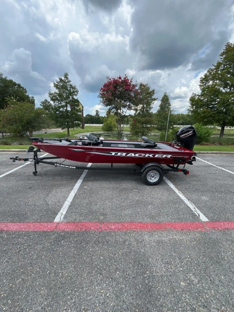 The Image of 2025 Tracker Panfish 17 boat on trailer in parking lot, cloudy sky background. - 0