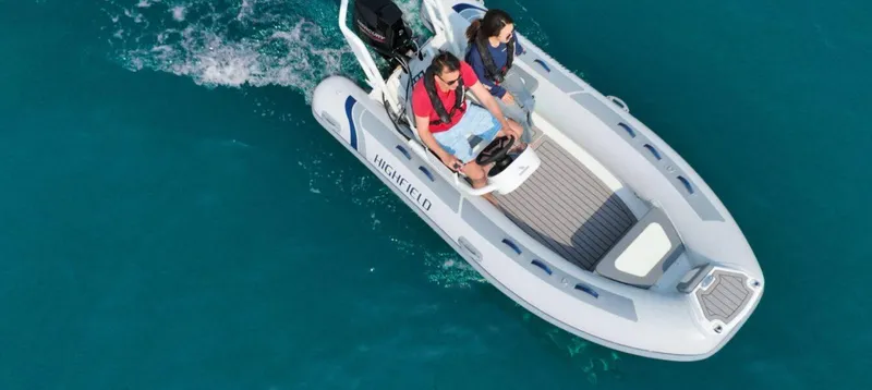 Slide: The Image of 2025 Highfield Classic 400 boat cruising on clear blue water, two people onboard. - 2